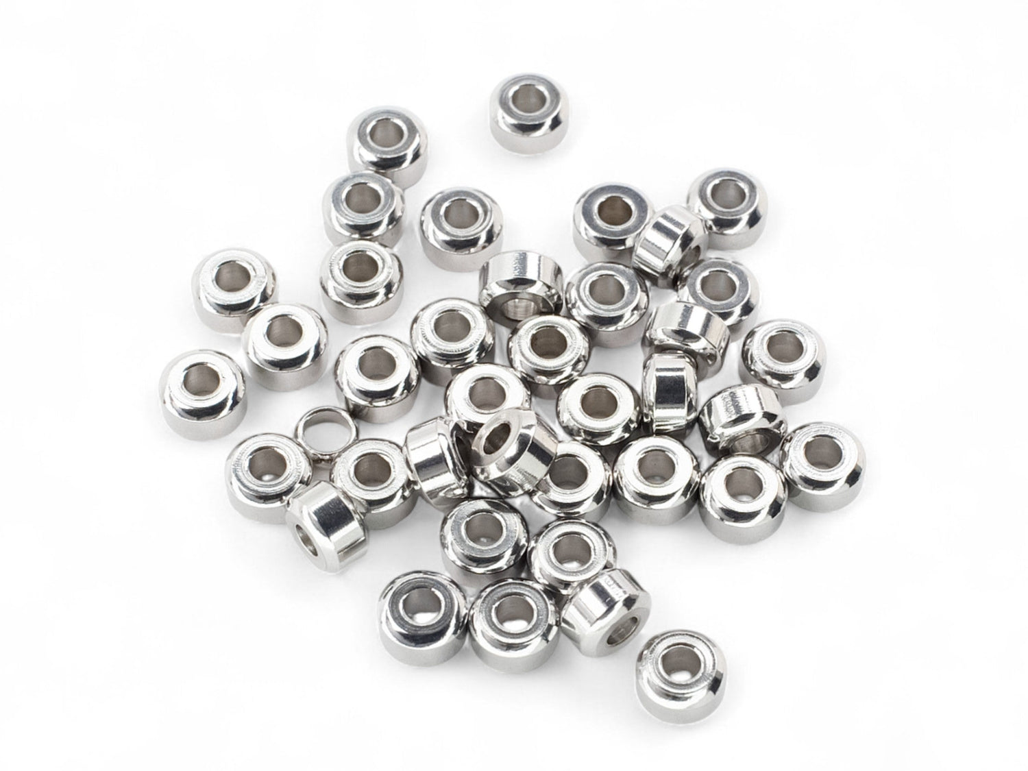 Collection of small beveled edge stainless steel metal beads on a white background
