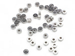 Collection of small stainless steel washer-type metal beads on a white background