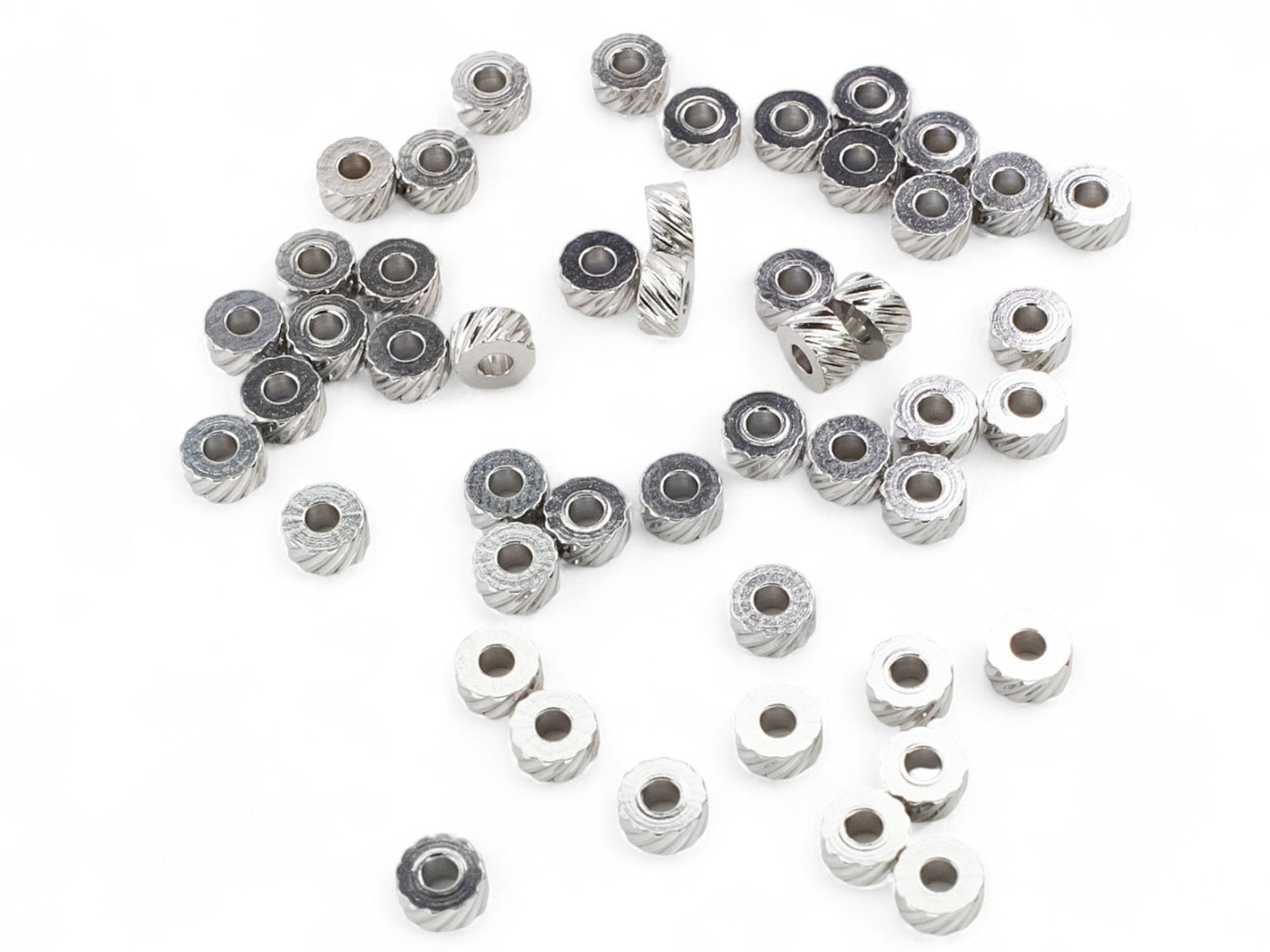 Collection of small stainless steel washer-type metal beads on a white background