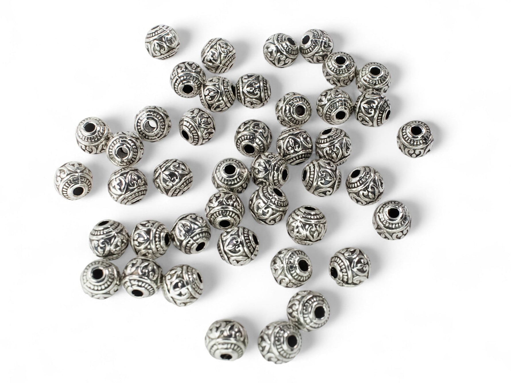 Tibetan silver round heart patterned spacer beads on white background