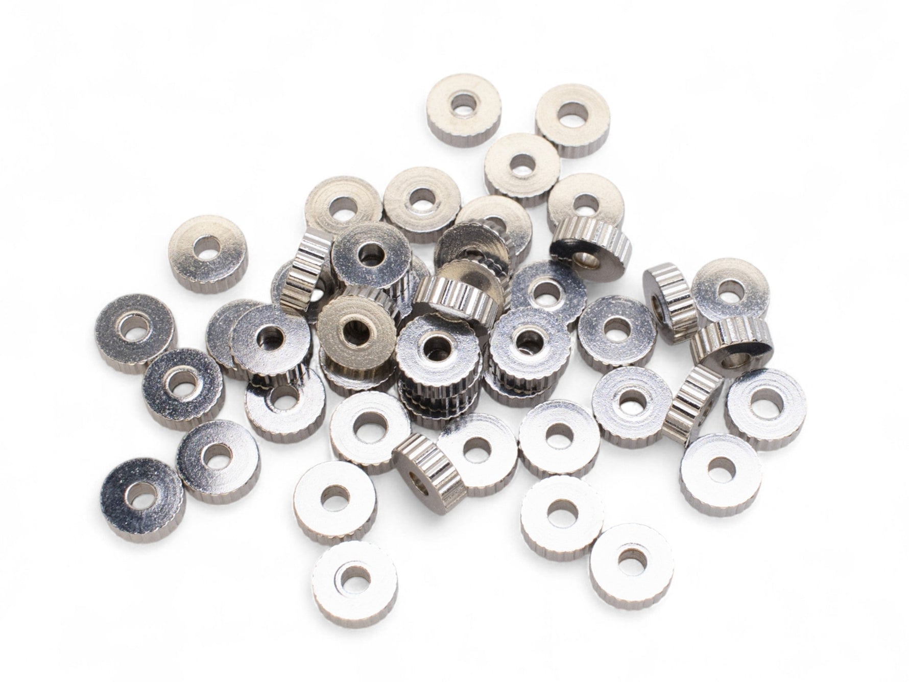 Collection of small silver spacer beads on a white background