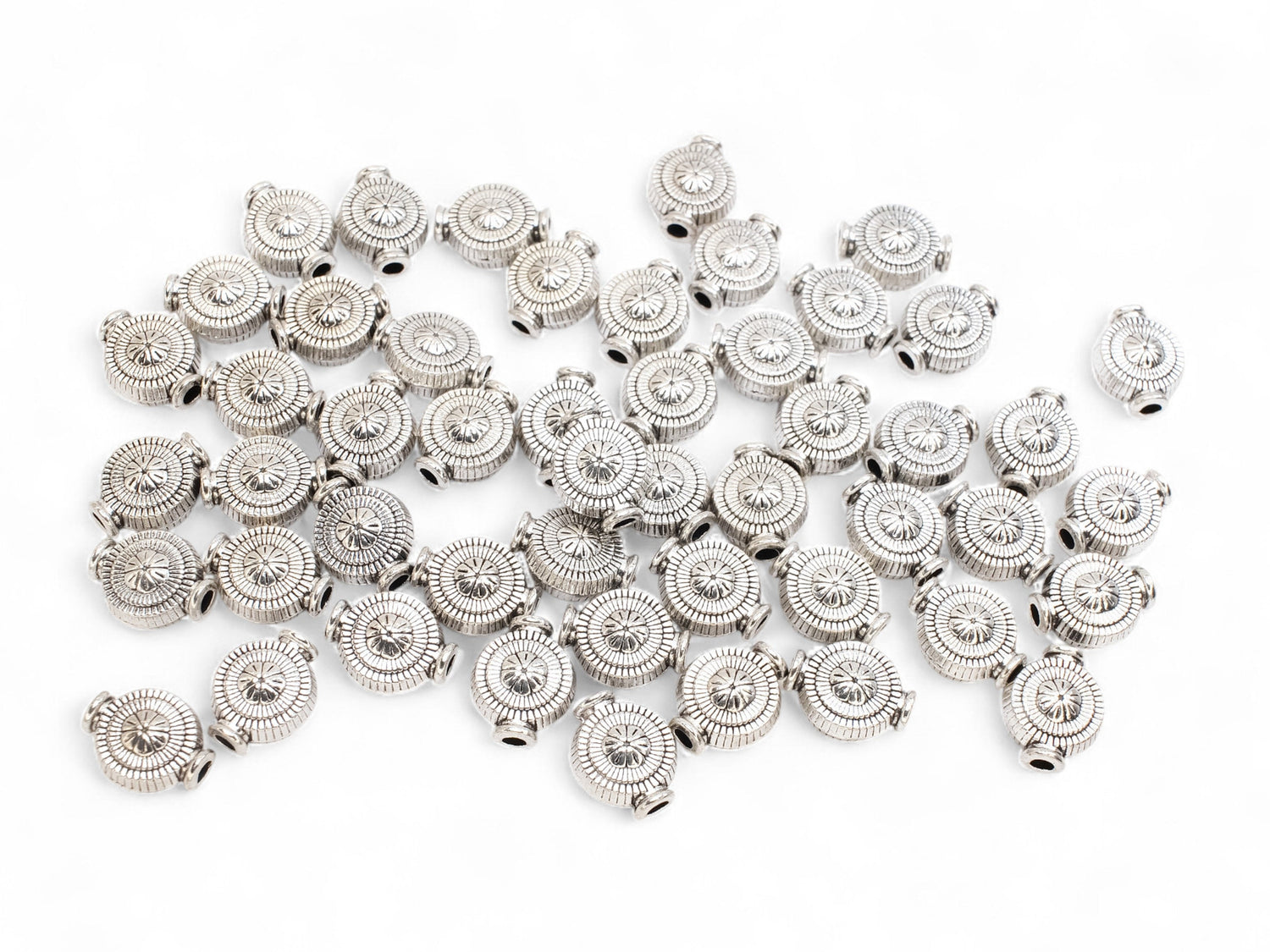 Tibetan Silver Sunburst Coin Spacer Beads in medallion shape on a white surface